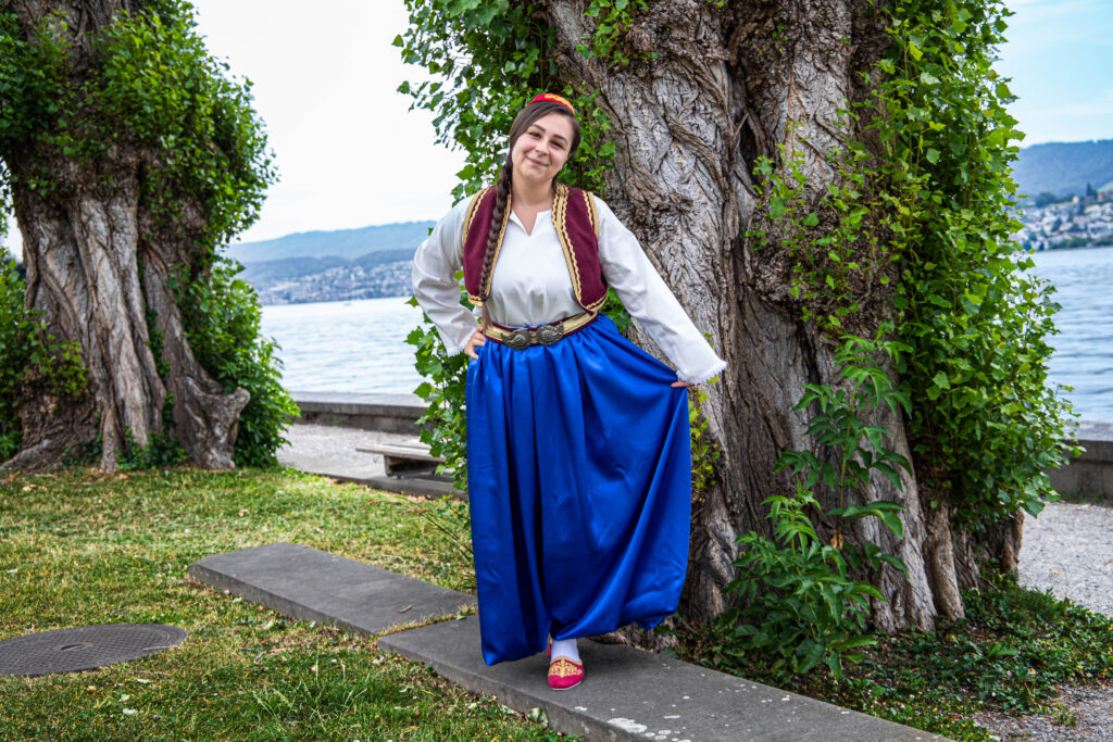 Frau in Tracht am See zwischen Bäumen