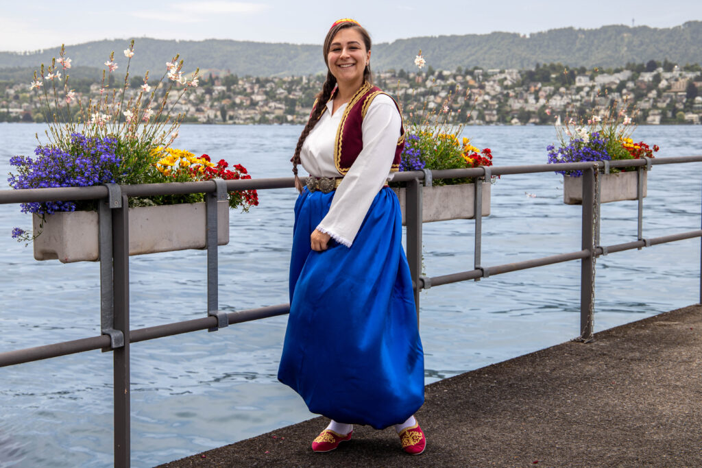 Frau in Tracht am Seeufer mit Blumen