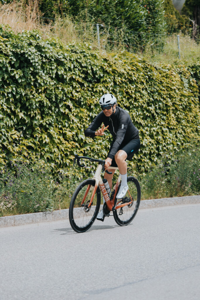 Cyclist with helmet on the road showing a peace sign